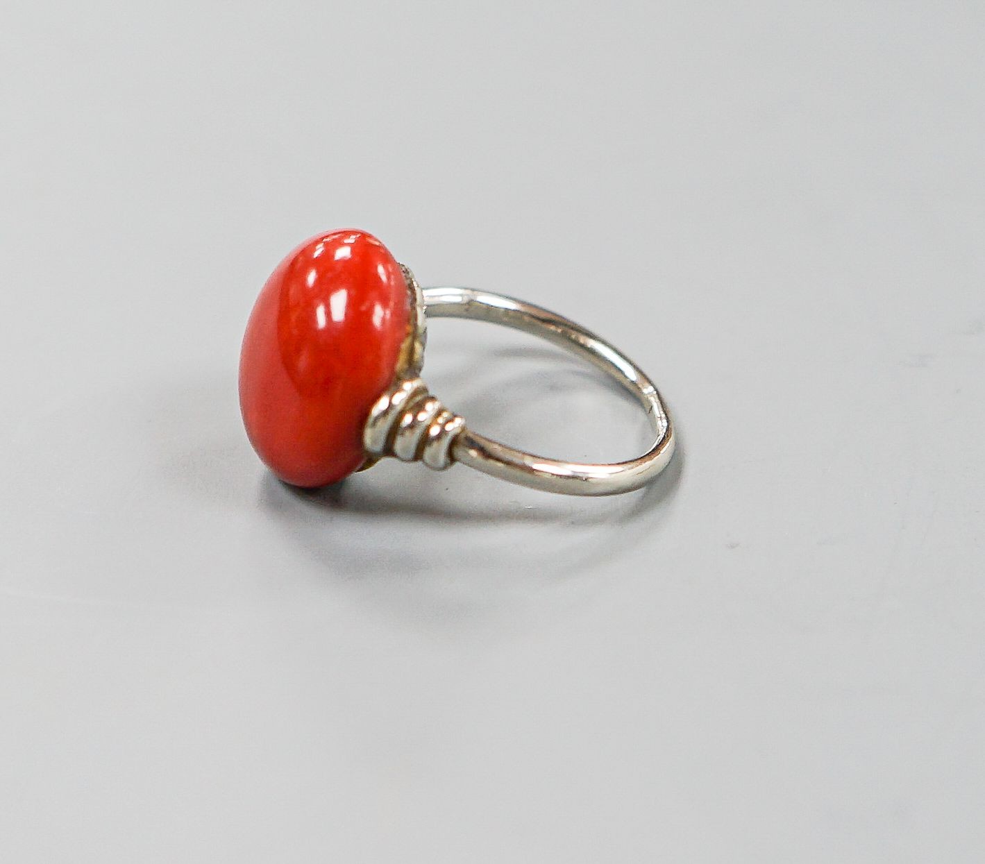 A 585 white metal and stained? cabochon coral set dress ring, size I, gross weight 5.5 grams.